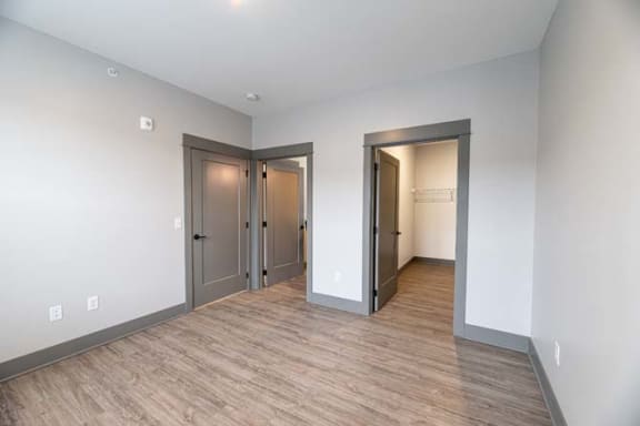a empty living room with a wooden floor and two doors at The Commons at Rivertown, Grandville, MI, 49418