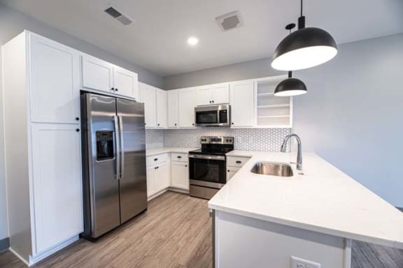 a white kitchen with a stainless steel refrigerator at The Commons at Rivertown, Grandville, MI