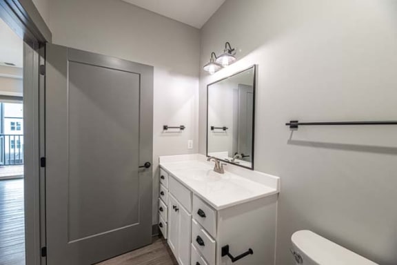 a white bathroom with a sink and a mirror at The Commons at Rivertown, Grandville, Michigan