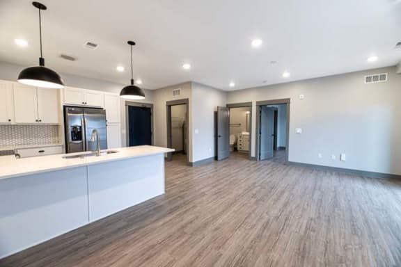 an empty kitchen and living room with a sink and refrigerator at The Commons at Rivertown, Grandville, 49418
