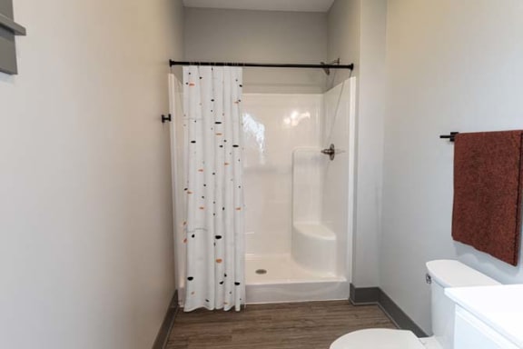 a bathroom with a shower and a toilet and a shower curtain at The Commons at Rivertown, Grandville, 49418