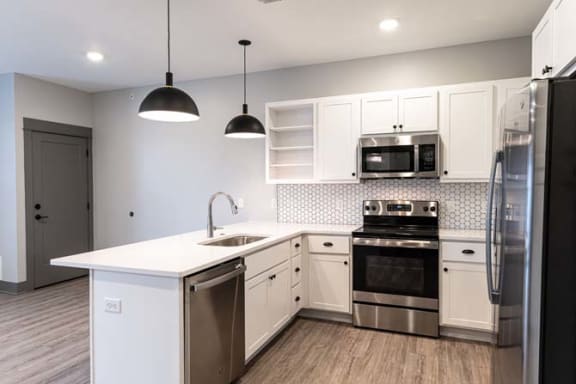 a kitchen with white cabinets and stainless steel appliances at The Commons at Rivertown, Grandville, Michigan