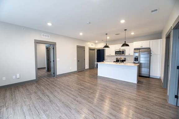 an empty living room and kitchen with a refrigerator and a sink at The Commons at Rivertown, Grandville, MI, 49418
