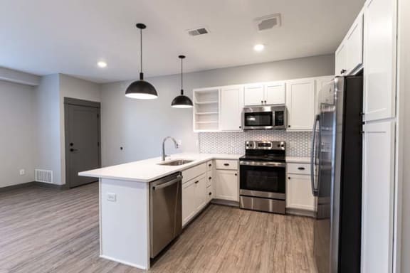 a kitchen with white cabinets and stainless steel appliances at The Commons at Rivertown, Grandville, Michigan