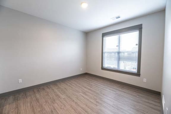 an empty room with a window and wood floors at The Commons at Rivertown, Grandville, MI, 49418