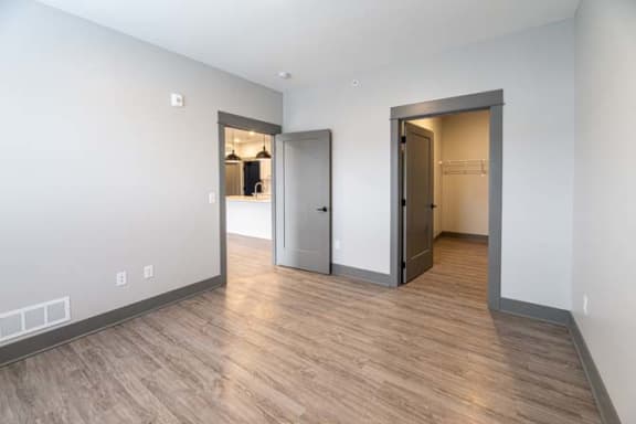 a empty living room with a door to a bedroom at The Commons at Rivertown, Grandville, MI, 49418