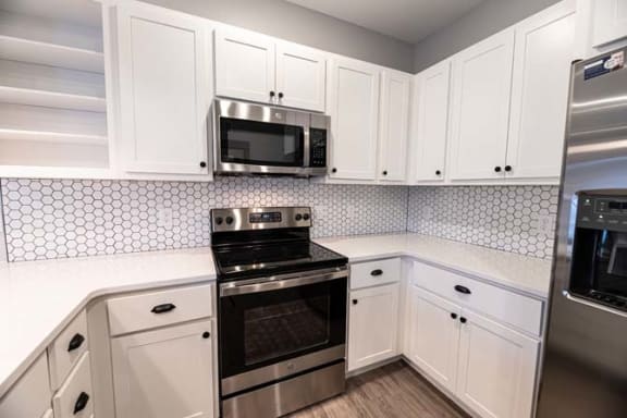 a white kitchen with a stove and a microwave at The Commons at Rivertown, Grandville, MI, 49418
