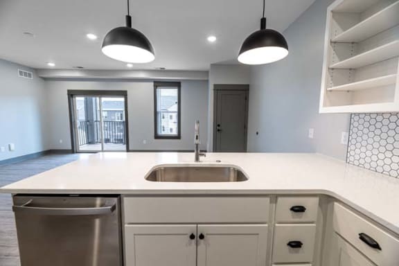 a white kitchen with two lights and a sink at The Commons at Rivertown, Grandville, Michigan