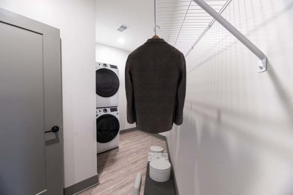 a bathroom with two washing machines and a sweater hanging on the wall at The Commons at Rivertown, Grandville, 49418