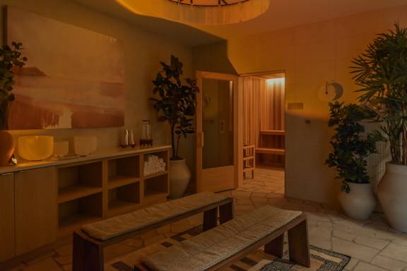 A room with a bench, a table, and a potted plant.