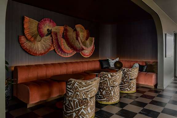 A room with a checkered floor and a wall with a large decorative piece.