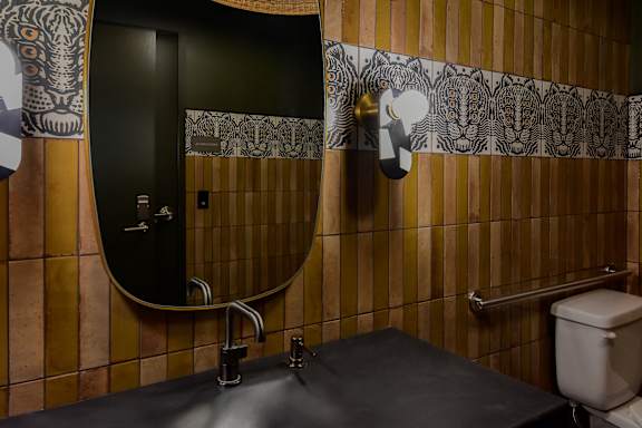 A bathroom with a black sink and a mirror with a black background.