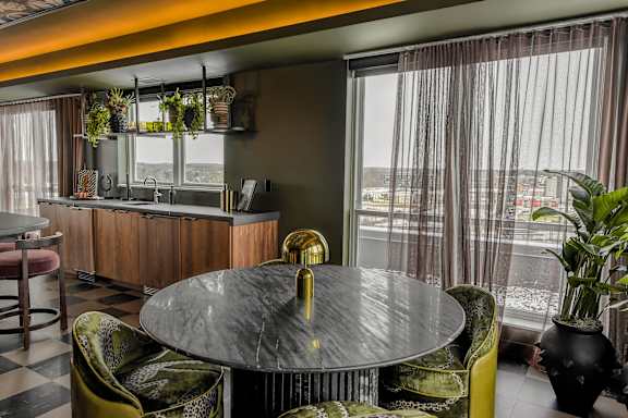 A round table with a gold handle sits in the middle of a room with a bar and chairs.
