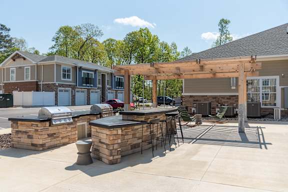 a patio with a bar and a grill in front of a house at The Bend Arbordale, Williamsburg, VA