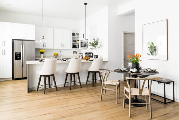 a kitchen and dining area with white cabinets and a table and chairs at Onyx at Westgate Apartments, Glendale