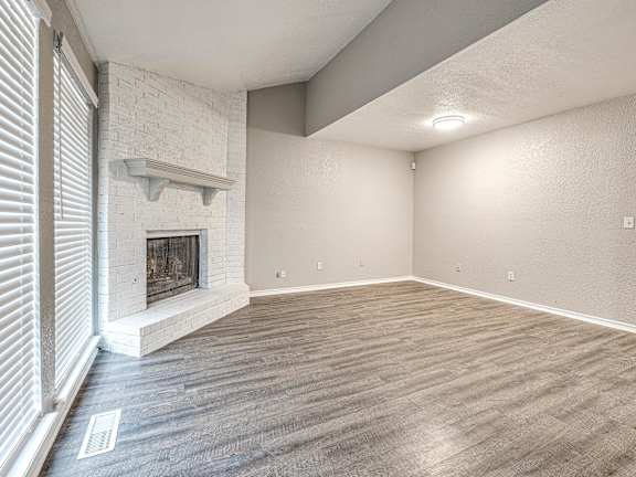 an empty living room with a fireplace and wood flooring at Diamond Ridge Townhomes, Oklahoma City, 73114