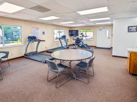 a gym with a table and chairs and a treadmill