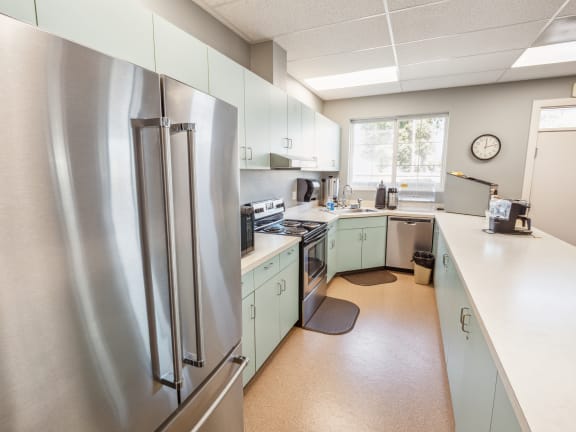 a kitchen with green cabinets and a stainless steel refrigerator