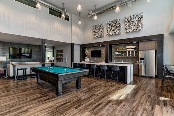 A room with a pool table and bar area.