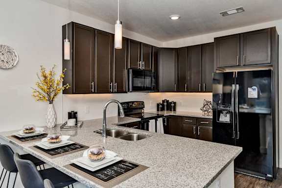 A kitchen with a granite countertop and a black fridge.