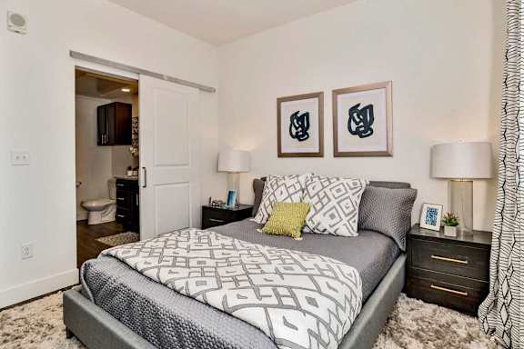 A bedroom with a large bed and two lamps.