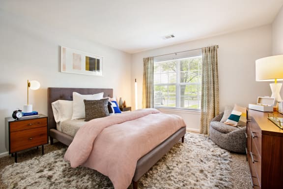 bedroom with bed with pink bedding and one window