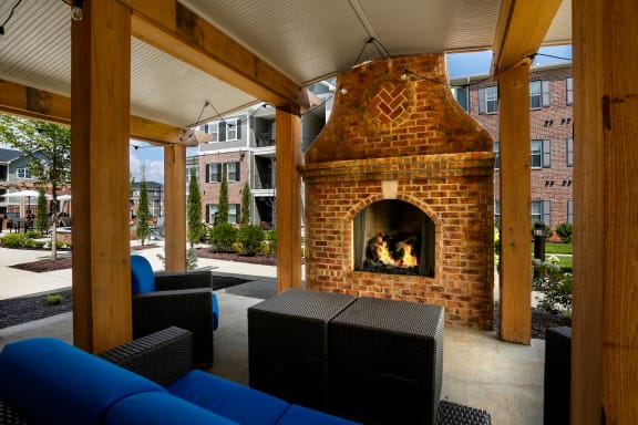 outdoor fireplace and seating with blue cushions under pergola at Annandale Apartment Homes, Tennessee 37128