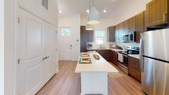 A kitchen with a white island in the middle and a refrigerator on the right.