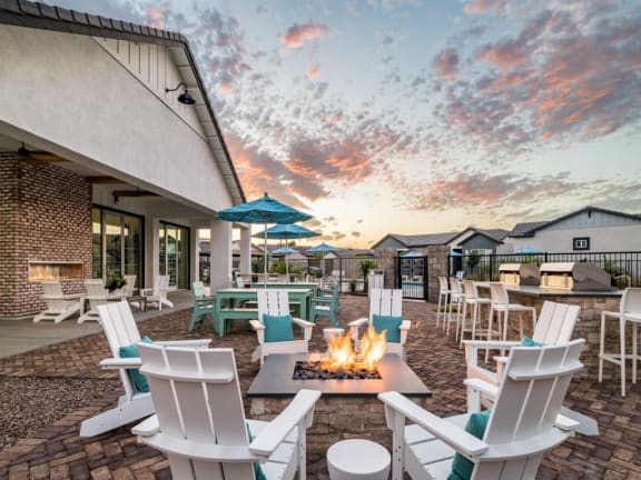 A patio with white chairs and a fire pit at Onyx at Westgate Apartments, Glendale, AZ