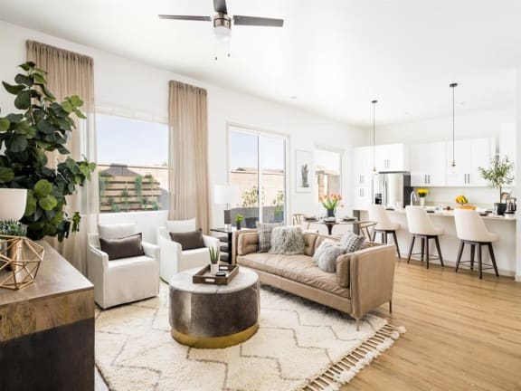 A modern living room with a large sectional sofa, a coffee table, and a dining area in the background at Onyx at Westgate Apartments, Glendale, AZ, 85305