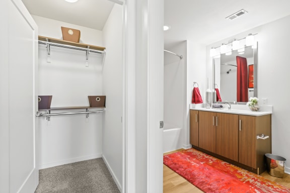 a bathroom with a shower sink and mirror and a red rug at 8000 Uptown Apartments, Colorado 80021