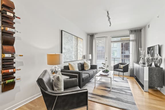 a living room with white walls and hardwood floors at 8000 Uptown Apartments, Broomfield
