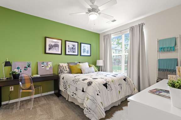 a bedroom with green walls and a white desk with a computer