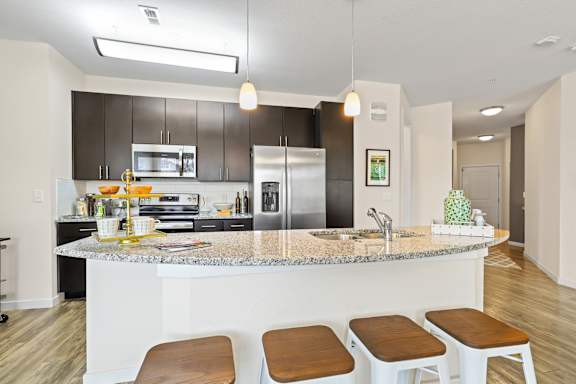 a kitchen with a bar and stools and a stainless steel refrigerator