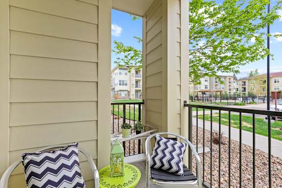 a patio with two chairs and a table with a bottle of water on it