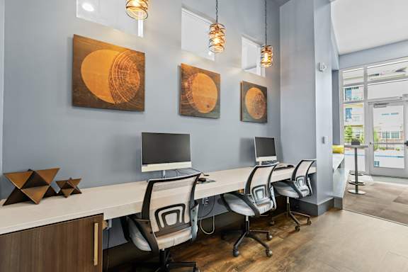 a row of computers on a long table with chairs in front of them