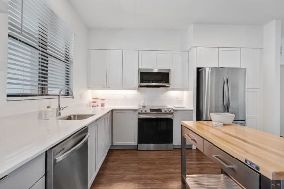 a kitchen with white cabinets and stainless steel appliances and a wooden counter top at Odyssey, Florida