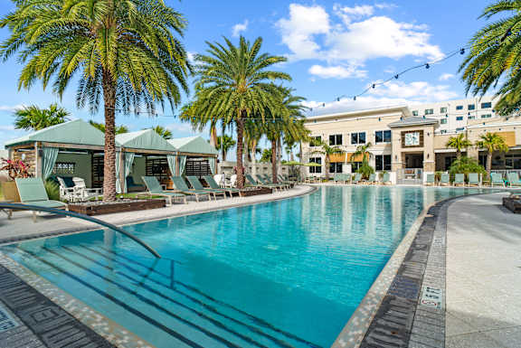 A large swimming pool surrounded by palm trees and lounge chairs. at Centre Pointe Apartments, Melbourne