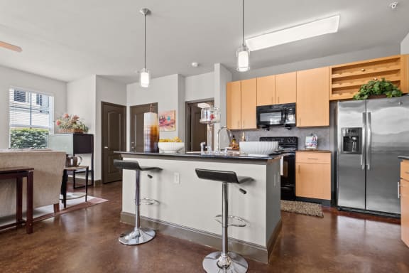 a kitchen with stainless steel appliances and an island with bar stools at The Millennium Towne Center Apartments, Baton Rouge, 70806