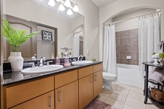 a bathroom with two sinks and a toilet and a shower at The Millennium Towne Center Apartments, Baton Rouge, LA, 70806