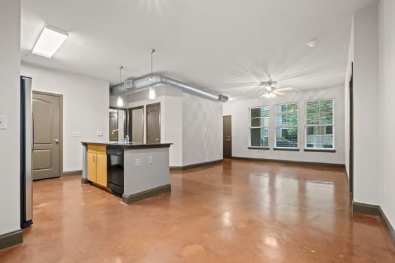 an empty living room with a kitchen and a large window at The Millennium Towne Center Apartments, Baton Rouge, 70806