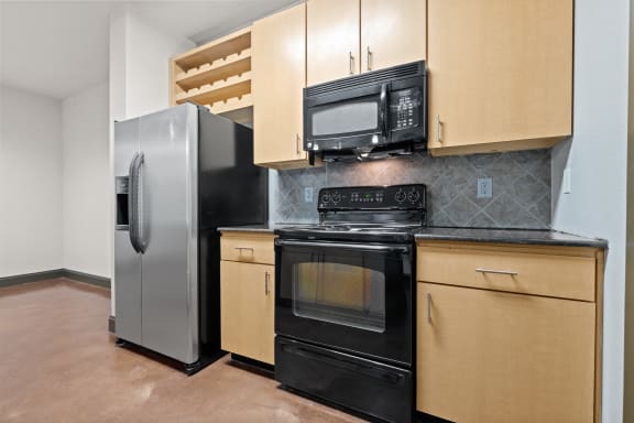 a kitchen with stainless steel appliances and wooden cabinets at The Millennium Towne Center Apartments, Baton Rouge, LA