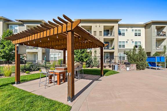 a patio with a pergola and tables in front of an apartment building