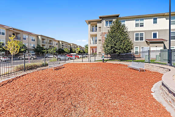 a fenced in dog park in front of an apartment building