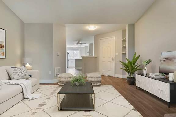 A living room with a white couch, a coffee table, and a plant at The Village at Seeley Lake Apartments, Lakewood, WA 98499