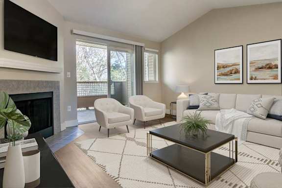 A living room with a fireplace and a white couch at The Village at Seeley Lake Apartments, Lakewood, WA