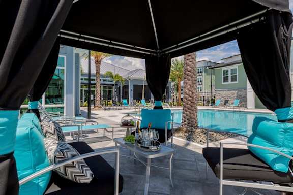 a swimming pool with blue chairs and tables at The Addison on Long Bayou Apartments, Florida, 33772