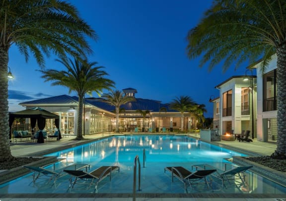 A large swimming pool surrounded by palm trees and lounge chairs at The Addison on Long Bayou Apartments, Seminole