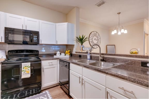 a kitchen with white cabinets and black appliances at Magnolia Village Apartments, Jacksonville, FL
