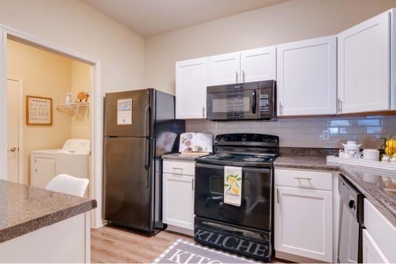 a kitchen with white cabinets and black appliances at Magnolia Village Apartments, Florida 32207